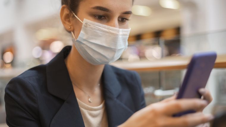 Woman with face mask looking at mobile phone
